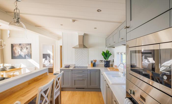 Kitchen with oven and built in microwave, hob, sink and breakfast bar.